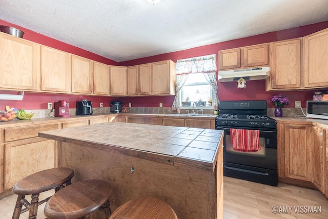 kitchen with sink, black range with gas cooktop, light hardwood / wood-style floors, a textured ceiling, and a kitchen island