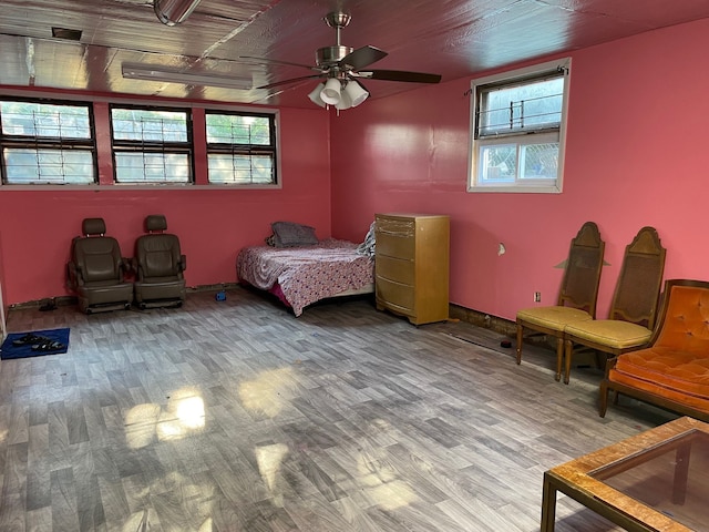 bedroom featuring ceiling fan, wood-type flooring, and multiple windows