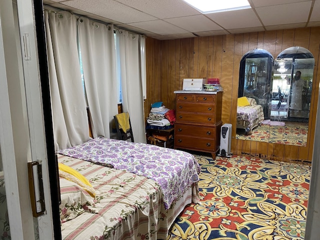 bedroom featuring wood walls and a drop ceiling