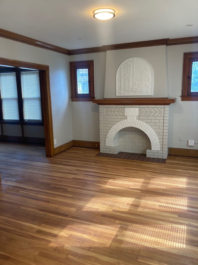 unfurnished living room with crown molding, wood-type flooring, and a fireplace