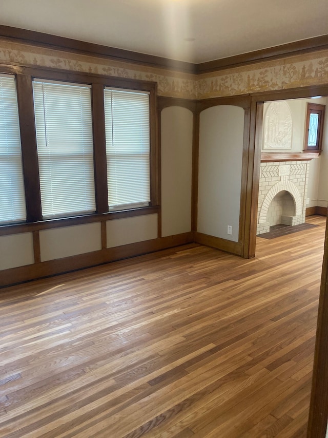 unfurnished living room featuring wood-type flooring and a brick fireplace