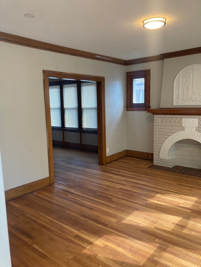 unfurnished living room featuring crown molding, wood-type flooring, and a brick fireplace