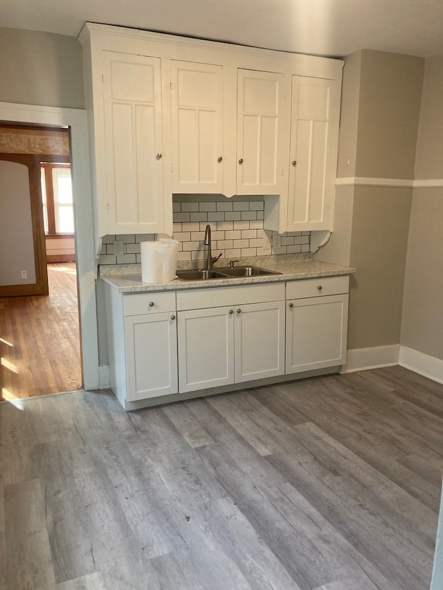 kitchen with white cabinets, sink, and light hardwood / wood-style flooring