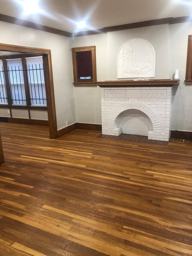 unfurnished living room with dark hardwood / wood-style flooring and a brick fireplace