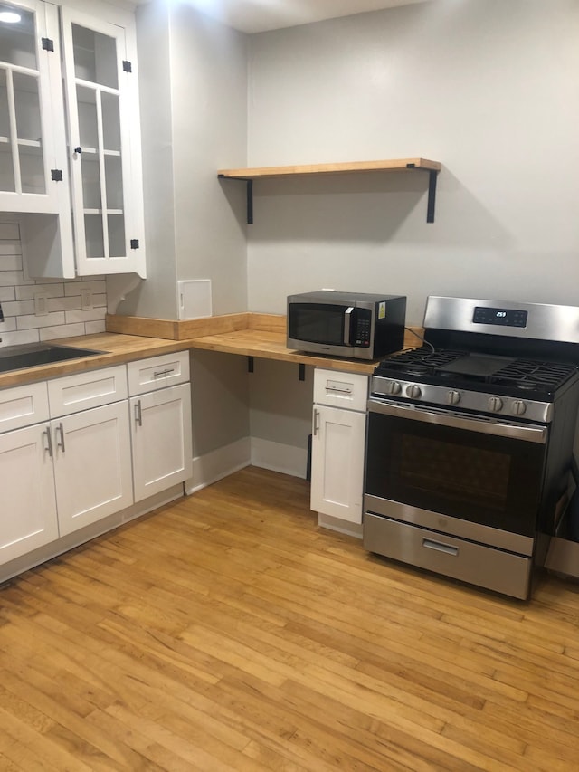 kitchen featuring butcher block counters, sink, decorative backsplash, white cabinets, and appliances with stainless steel finishes