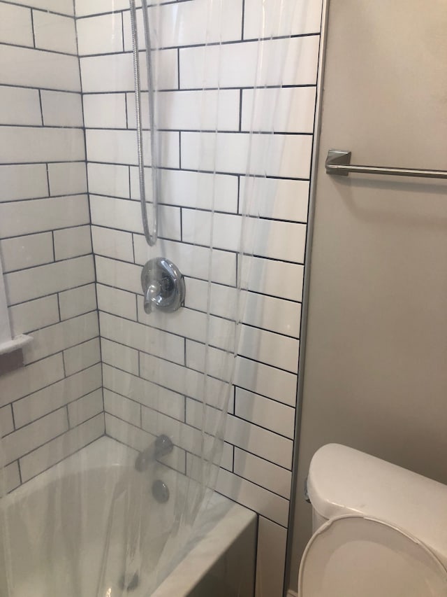 bathroom with toilet and tiled shower / bath