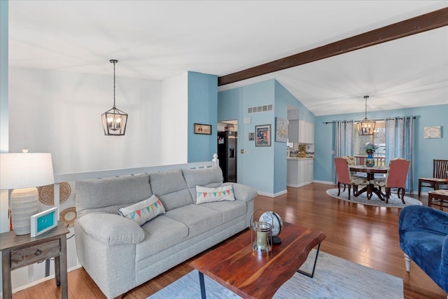 living room featuring lofted ceiling with beams, an inviting chandelier, and wood-type flooring