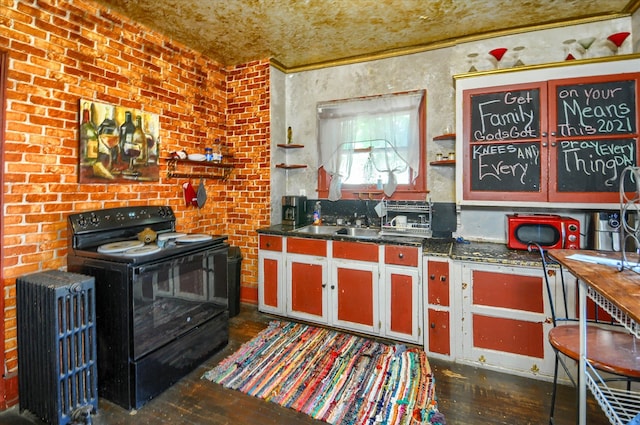 kitchen with black electric range, radiator, dark wood-type flooring, and brick wall