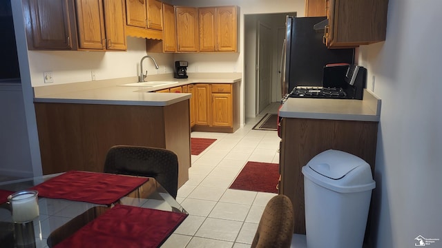 kitchen featuring light tile patterned flooring, stove, and sink