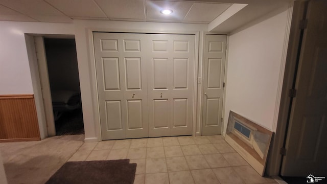 interior space featuring light tile patterned floors, a paneled ceiling, and wood walls