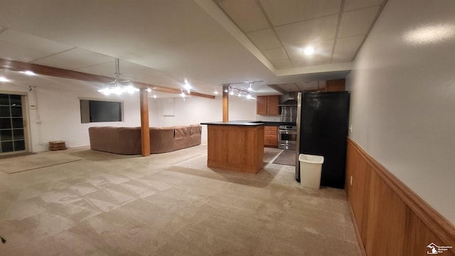 basement featuring light colored carpet, stainless steel refrigerator, and wood walls