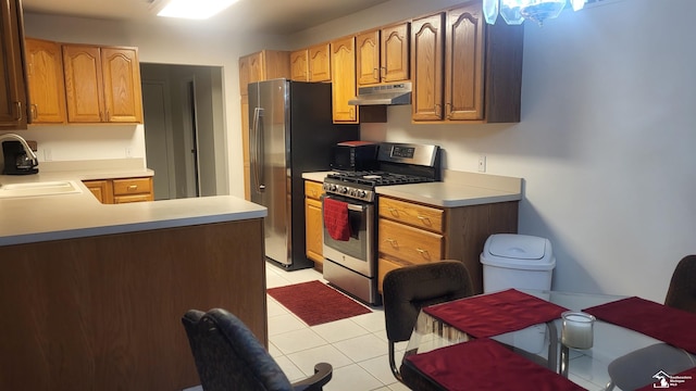 26926 Reaume, Trenton, MI 48183 - kitchen with stainless steel appliances, under cabinet range hood, light countertops, light tile patterned floors, and a peninsula