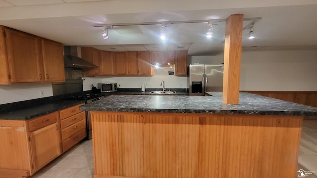 kitchen with sink, rail lighting, stainless steel appliances, a center island, and wall chimney exhaust hood