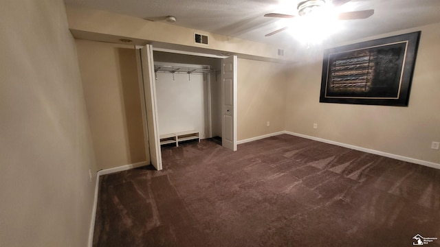 unfurnished bedroom featuring dark carpet, ceiling fan, and a closet