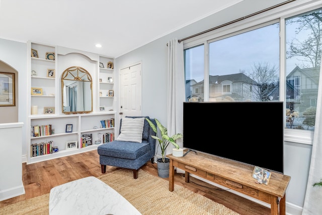 sitting room featuring built in features, crown molding, and light hardwood / wood-style flooring