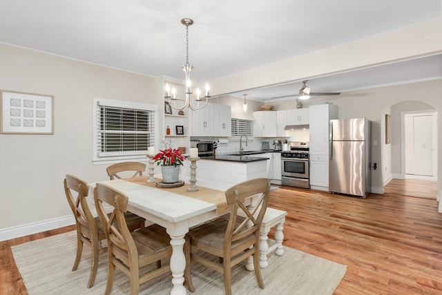 dining area with a notable chandelier, sink, and light hardwood / wood-style flooring