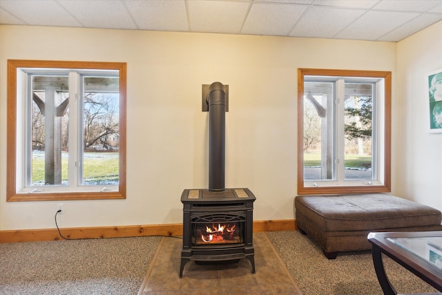 living room with a drop ceiling and a wood stove