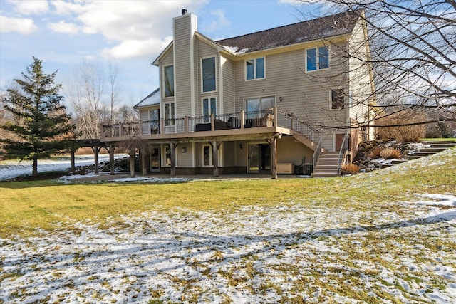 snow covered house with a patio, a lawn, and a wooden deck