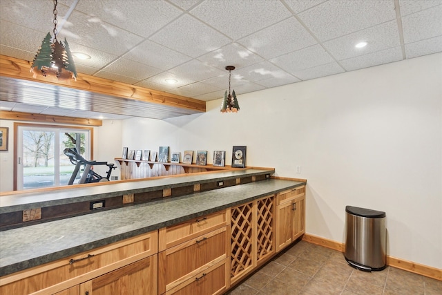 bar with tile patterned floors, a paneled ceiling, and pendant lighting