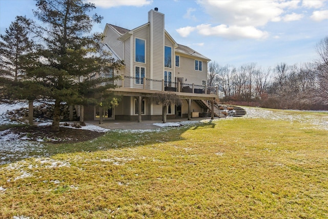 back of house featuring a lawn, a wooden deck, and a patio area