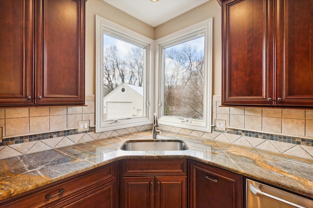 kitchen featuring decorative backsplash, light stone counters, a wealth of natural light, and sink