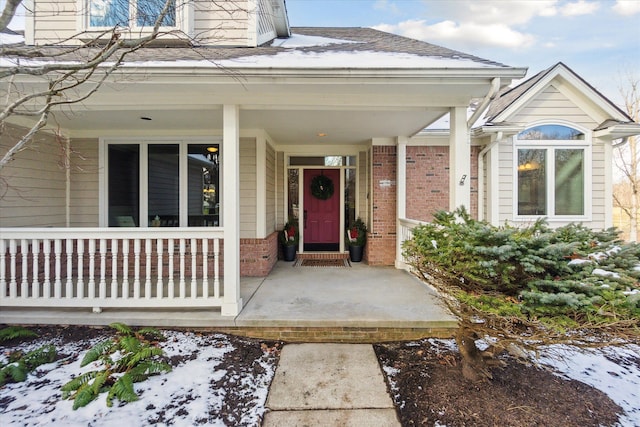 snow covered property entrance featuring a porch