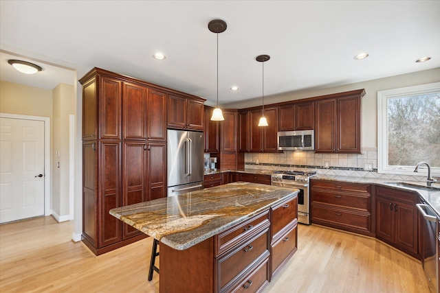 kitchen with sink, light hardwood / wood-style floors, high quality appliances, a breakfast bar, and a kitchen island