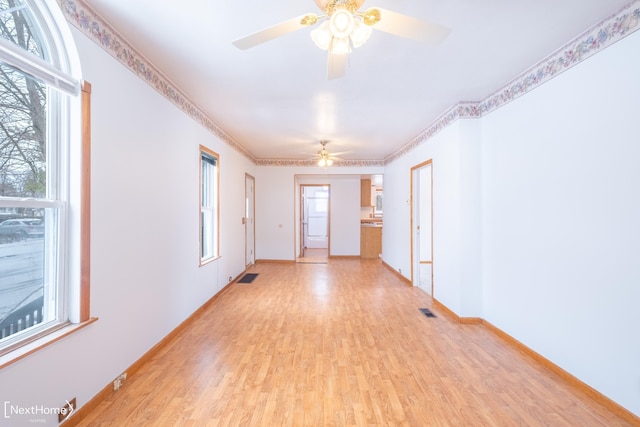 spare room featuring light hardwood / wood-style flooring, a wealth of natural light, ornamental molding, and ceiling fan