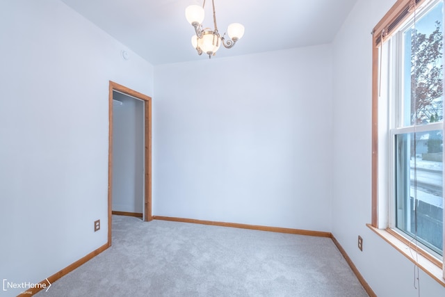 unfurnished room featuring a chandelier and light carpet