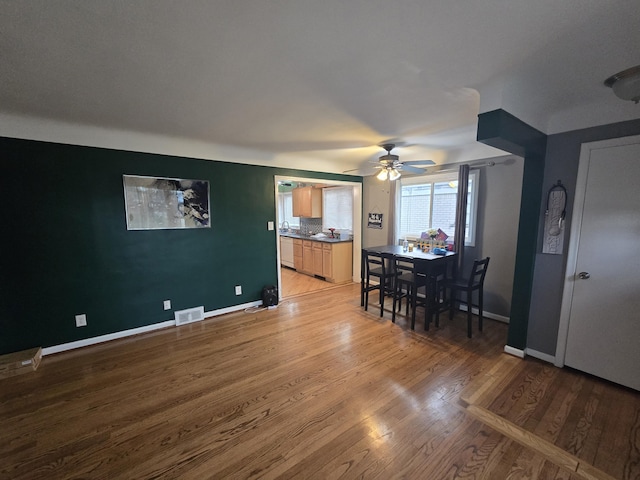 dining space with hardwood / wood-style flooring, ceiling fan, and sink