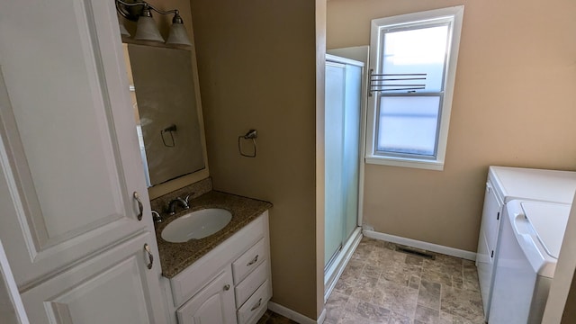 2521 Hillside Dr NW, Grand Rapids, MI 49544 - full bath featuring washing machine and dryer, vanity, a stall shower, baseboards, and stone finish flooring