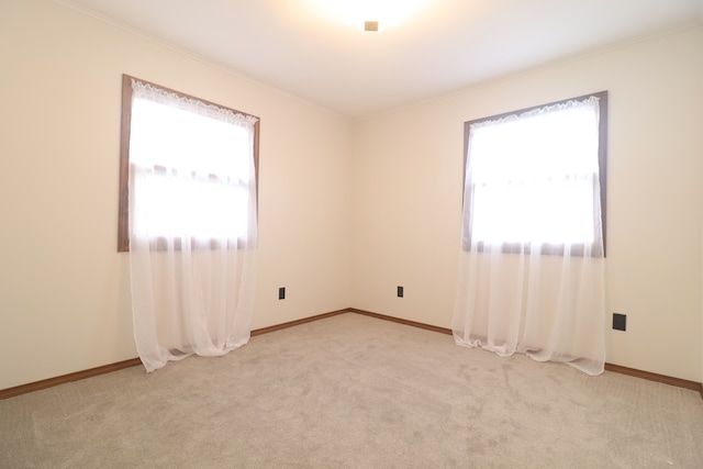 unfurnished room featuring light colored carpet, ornamental molding, and a wealth of natural light