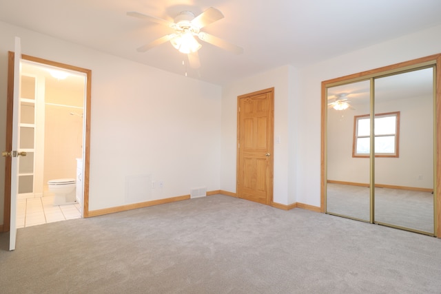 unfurnished bedroom featuring ceiling fan, light colored carpet, and connected bathroom