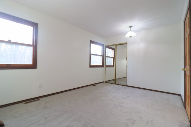 unfurnished room with light carpet and a chandelier