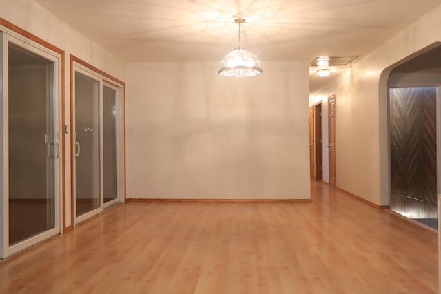 spare room with wood-type flooring and an inviting chandelier