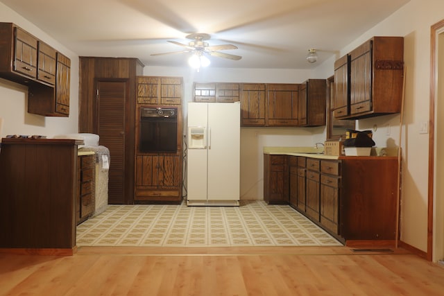 kitchen featuring dark brown cabinets, light hardwood / wood-style flooring, oven, and white refrigerator with ice dispenser