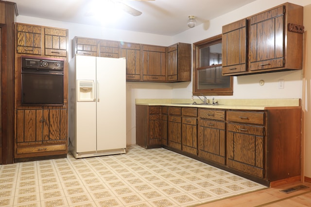 kitchen with ceiling fan, sink, white refrigerator with ice dispenser, light hardwood / wood-style floors, and black oven