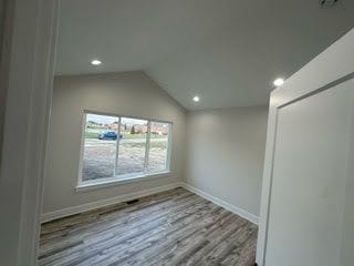 spare room featuring lofted ceiling and light hardwood / wood-style flooring