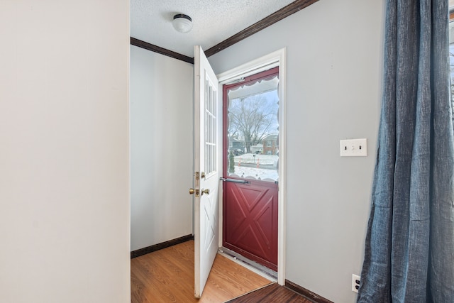 interior space with a textured ceiling, hardwood / wood-style flooring, and ornamental molding