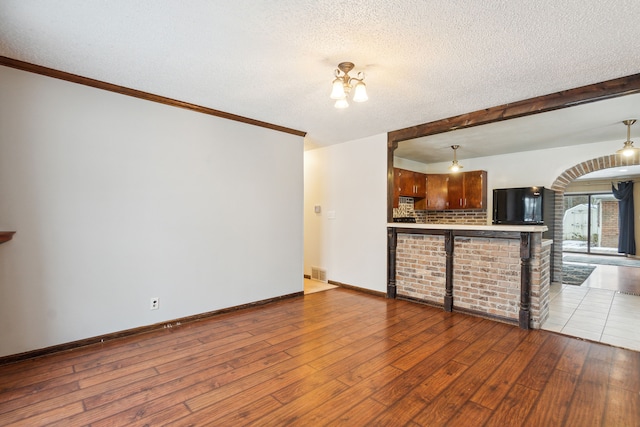 unfurnished living room featuring a textured ceiling, light wood-type flooring, and a notable chandelier