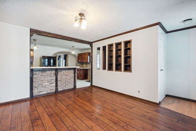 unfurnished living room featuring hardwood / wood-style floors, ornamental molding, and a textured ceiling