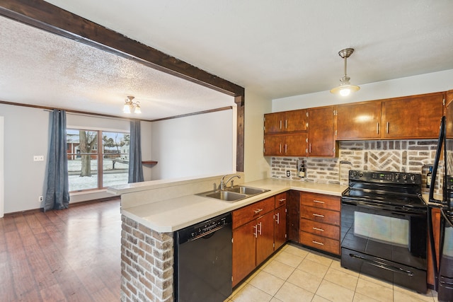 kitchen with sink, hanging light fixtures, kitchen peninsula, black appliances, and light wood-type flooring