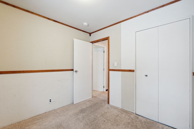 unfurnished bedroom featuring light colored carpet, a closet, and ornamental molding