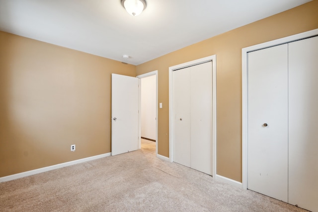 unfurnished bedroom with light carpet and multiple closets