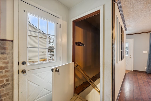 entryway with dark wood-type flooring, a textured ceiling, and ornamental molding