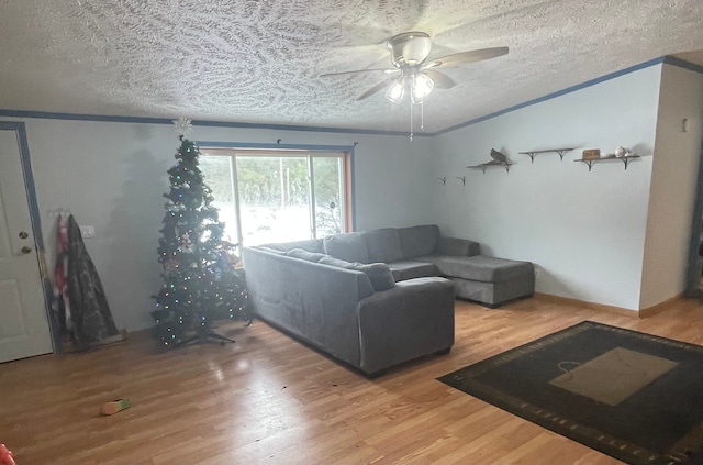 living room featuring crown molding, ceiling fan, wood-type flooring, and a textured ceiling