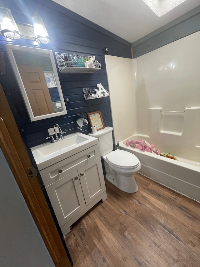 full bathroom with shower / tub combination, vaulted ceiling, hardwood / wood-style flooring, vanity, and toilet