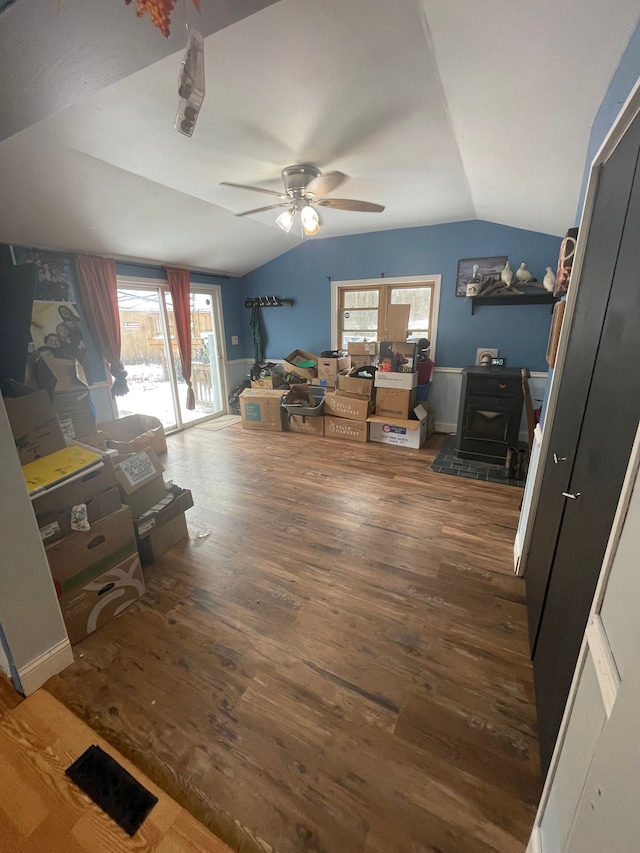 interior space featuring multiple windows, vaulted ceiling, dark hardwood / wood-style floors, and a wood stove