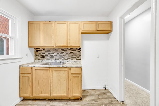 kitchen with sink, light hardwood / wood-style flooring, backsplash, light stone countertops, and light brown cabinets