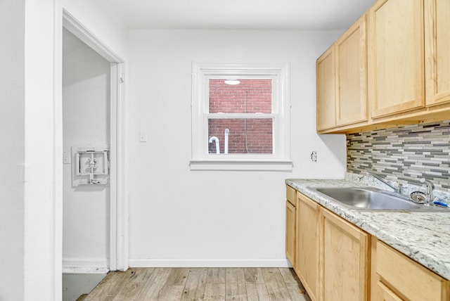 kitchen featuring sink, backsplash, light stone counters, light brown cabinets, and light hardwood / wood-style flooring